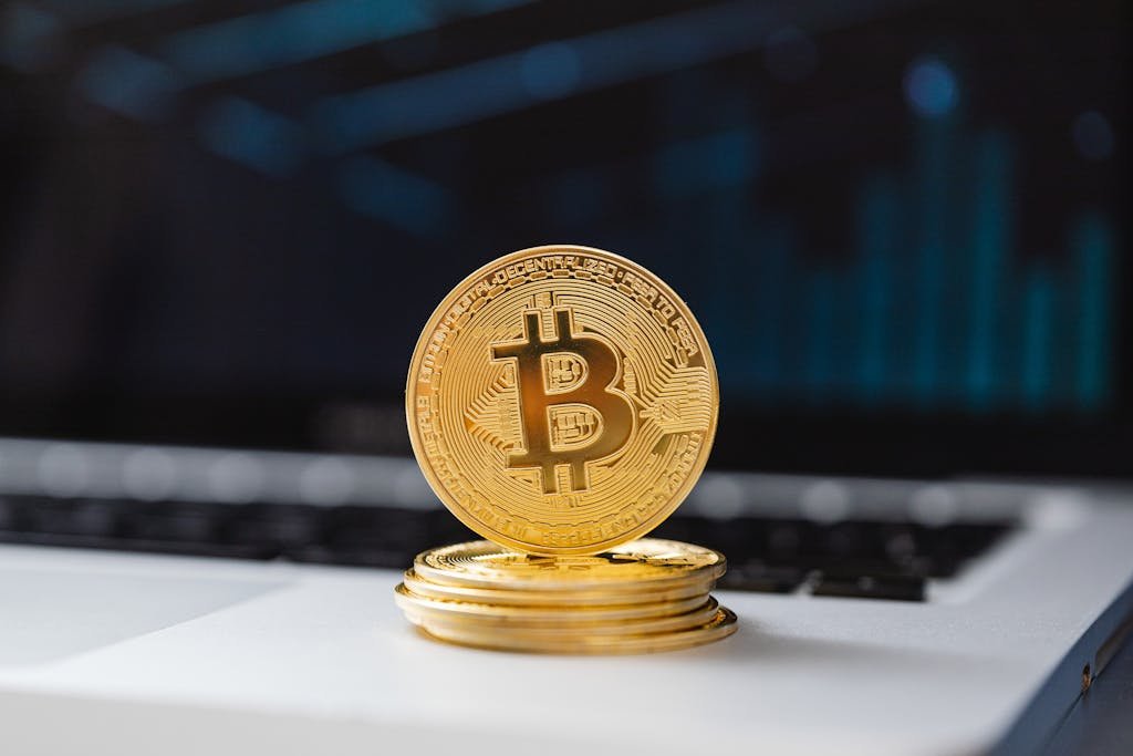 A shiny gold Bitcoin coin on laptop keyboard, symbolizing digital currency and blockchain technology.